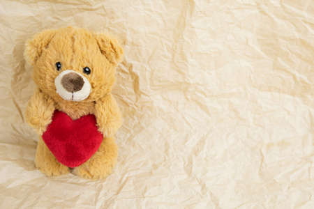 a teddy bear doll holding a heart-shaped pillow with loveの写真素材