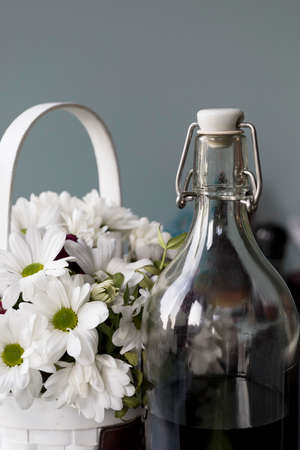 Homemade tincture of red cherries in a glass bottle on a gray background, close-up. The concept of berry alcoholic beveragesの写真素材
