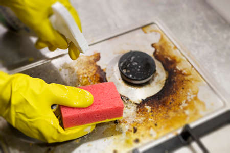 dirty kitchen stove, empty and full bottles of detergents around.の写真素材