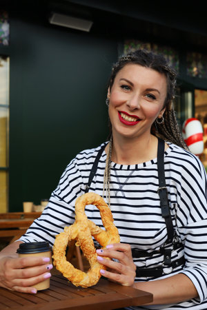 A young woman with a stylish hairstyle holds a bagel in her hands, brings a bagel to her eye with a...
