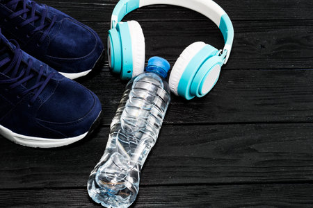 Bottle with water, smartphone, earphones and sneakers at a background. Set for sports activities.の写真素材