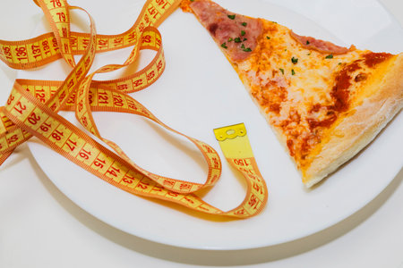 Pizza slice with measuring tape on white background. diet concept, healthy food concept