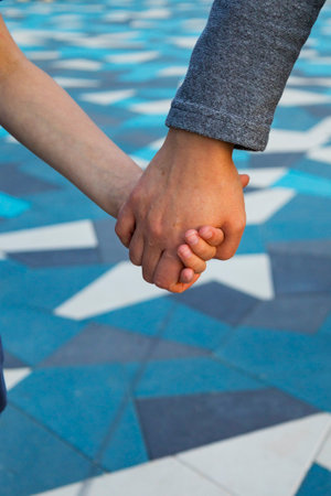 A man and a woman hold hands on a blue and white tiled floorの写真素材