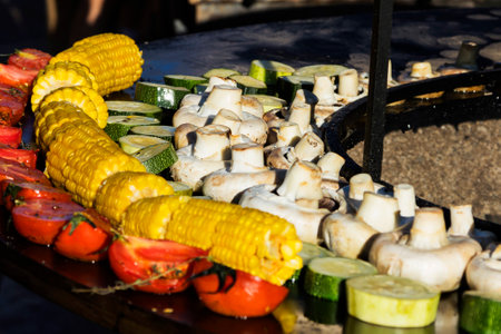 A person wearing black gloves is preparing food on a grill outdoors