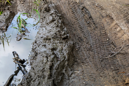 There is a muddy road that has a puddle of water situated in its middleの写真素材
