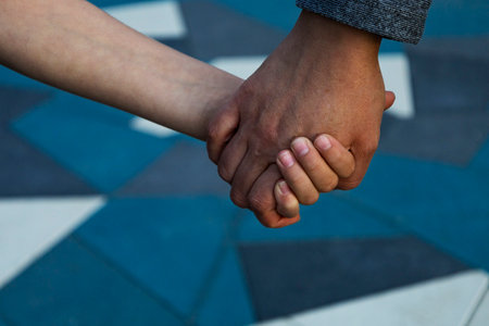 A man and a woman hold hands on a blue and white tiled floorの写真素材