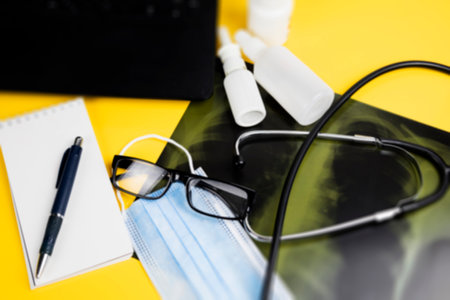 A stethoscope, mask, glasses, pen, and notebook are on a tableの写真素材
