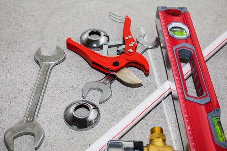 On the floor, there is a pair of metal wrenches and a pipe cutter
