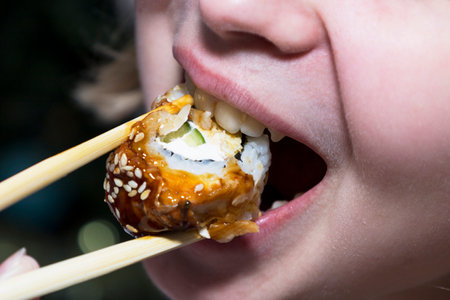 A detailed closeup view of a person relishing sushi with chopsticksの写真素材