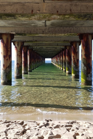 View of ocean under pier with sandy beach in the foregroundの写真素材