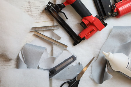 A collection of sewing and upholstery tools, including scissors and fabric pieces, ideal for DIY...