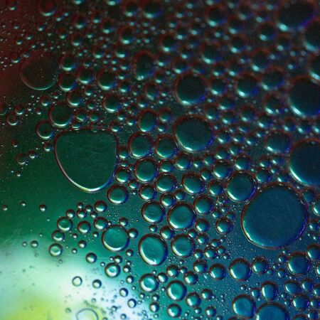 Oil bubbles on the water surface close-up with illumination.