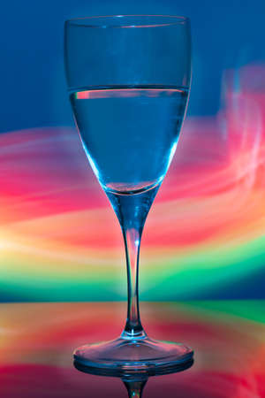 A beautiful glass is on the table. The background is blurred with light from the phone screen.の写真素材