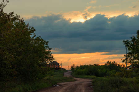 The winding dirt road goes into the horizon against the cloud sky. The photo was taken near the town of Kopeisk, Chelyabinsk region, Russia.の写真素材