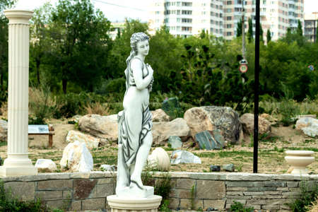 Stone statues and antique columns against the background of trees and buildings. Photo taken in Chelyabinsk, Russia.の写真素材