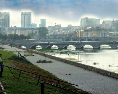 Landscape, view of the river in the center of the city, Photo taken on the banks of the river Miass, Chelyabinsk, Russia. Translation of the inscription on the roof of the building: "Arkaim Plaza" and "Cascade."の写真素材