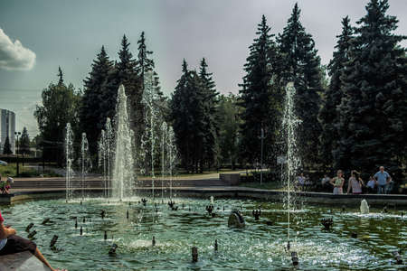 A working fountain and people resting around it.のeditorial素材