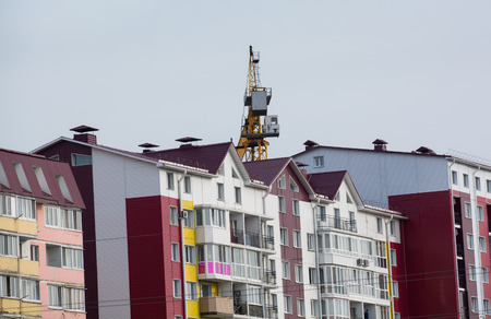 Colored residential home. Tower hoisting cranes over buildingの写真素材