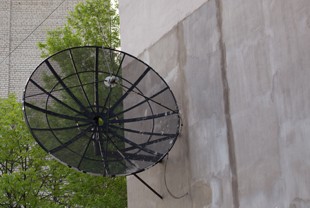 Black antenna dish on the wall of houseの写真素材