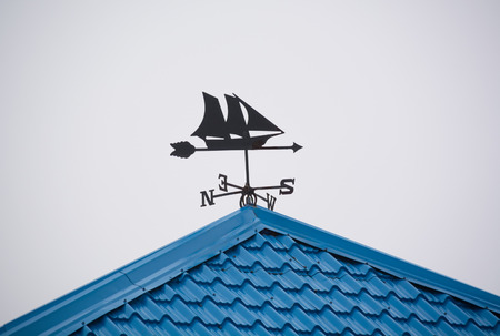 Blue rooftop with a ship weather vane pointing southの写真素材