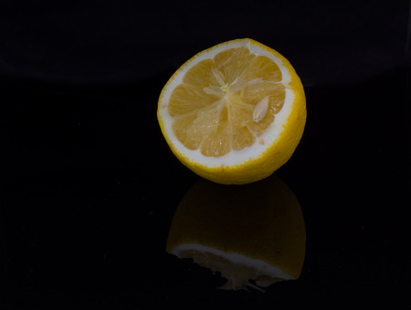 Half of fresh lemon reflects from the dark surfaceの写真素材