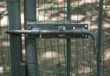 Old rusty metal fence closed with latch lockの写真素材