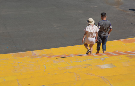 Two people down the stairs. Men and woman walk down under vibrant yellow staircase.の写真素材