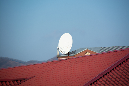 White satellite antenna mounted on the roof ridge. Minimalistic image.の写真素材