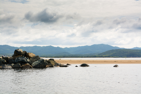 Pile of boulders in a small sea backwater. Hills and sky on background.の写真素材