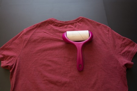 Adhesive Roller For Cleaning Cloth On a T-shirt. Lint Roller With Pink Handle.の写真素材