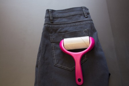 Adhesive Roller For Cleaning Cloth On a Pants. Lint Roller With Pink Handle.