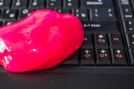Keyboard cleaning gel is laying on the keyboard. Notebook and pink gel.の写真素材