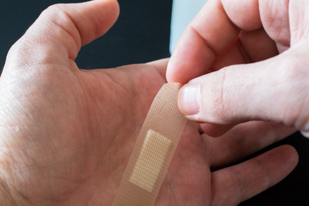 Adhesive Bandage on Men's Finger. Black Background.
