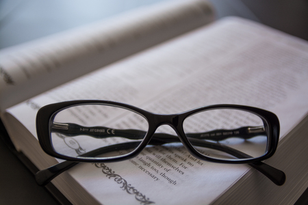 Glasses on the Open Book. Close-Up of Black Glasses.の写真素材