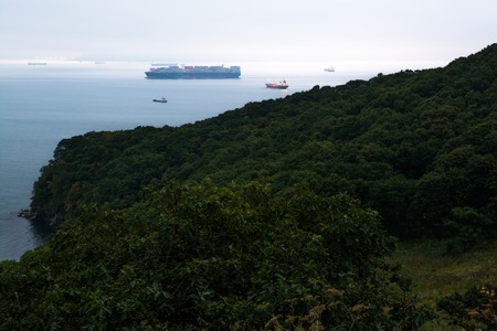 Few nautical ships in a harbor at early morning. Big container ship anchored in the sea bay.の写真素材