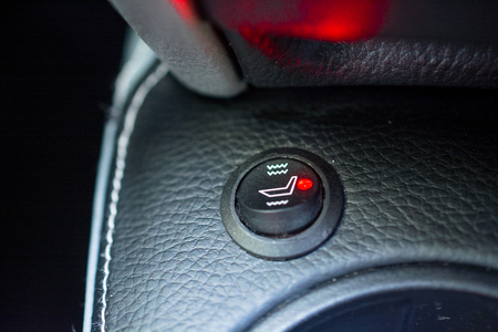 Switcher of car's heated seats. Black button with pictogram and green diode lamp.の写真素材