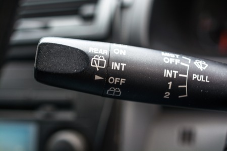 Row of knobs on a car dashboard. Black panel with two vivid orange and green light.の写真素材