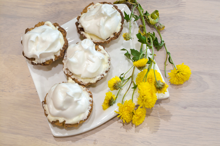 Several cakes basket with whipped cream. Yellow flowers near.の写真素材