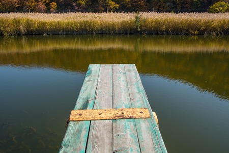 View from the jetty over a calm lake. Small weathered wooden pier.の写真素材