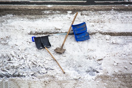 Plastic snow shovel in a snow bank on pavement. Snow removing tools.の写真素材