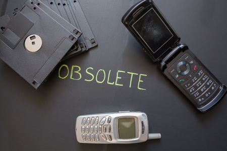 Old mobile phones and floppy disks on dark background. Obsolete electronic equipment.の写真素材