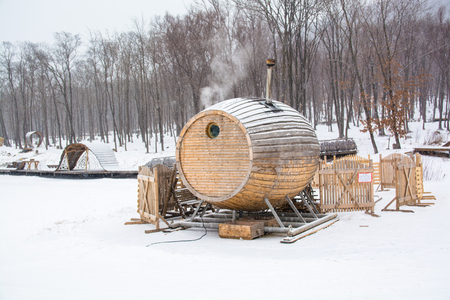 Unusual wooden sauna among snow. Bathhouse in shape of barrel. Snowy winter day.の写真素材
