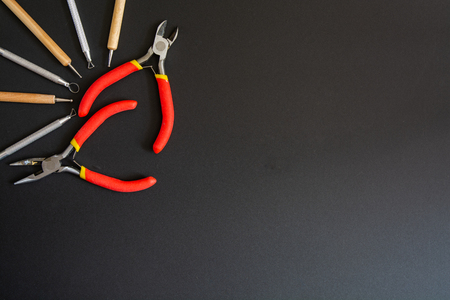 Art tools in a top left corner. On a black background. Small pliers, cutting pliers and stacks.の写真素材