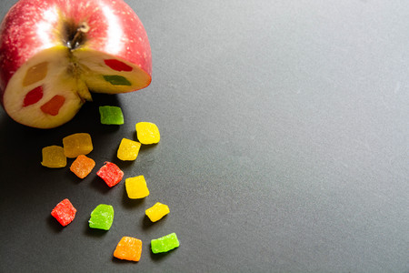 The apple with a candied fruit inside. Incised apple in top left corner of black background.の写真素材