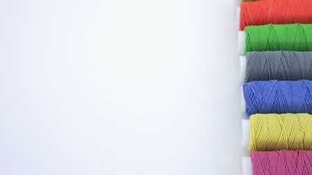 Multicolored coils of thread lie on a white