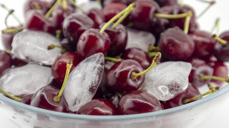 cherry berries in a plate with ice on a white backgroundの写真素材