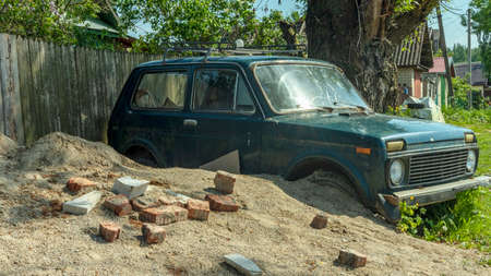 an old abandoned green car is covered with sand