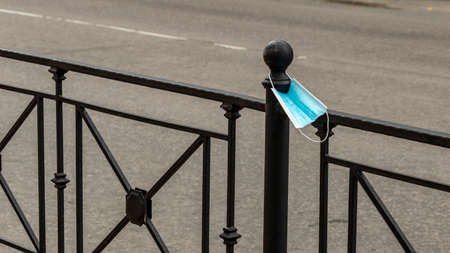 a new medical mask hangs on the road railing