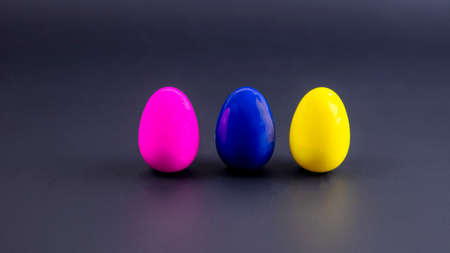 three multi-colored small eggs on a black backgroundの写真素材