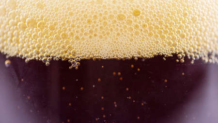 foam of dark beer in a glass glass, macro photography, backgrounds,